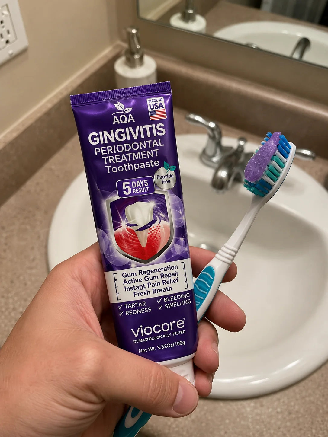 AQA VioCore toothpaste held next to a toothbrush at a bathroom sink
